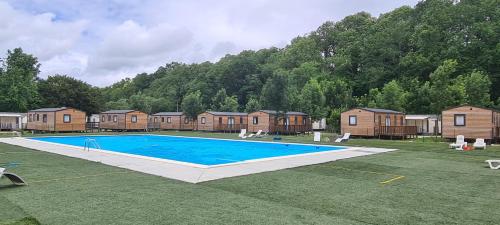 a large swimming pool in a yard with houses at Camping Le Pré Cathare in Lavelanet