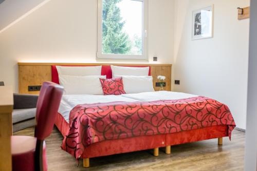 a bedroom with a red and white bed with a window at Landhotel zum Baggernpuhl in Wachow