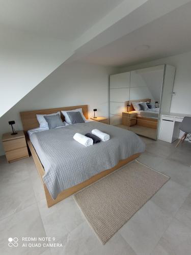 a bedroom with a large bed with two towels on it at Velobaltica apartmenty in Wisełka
