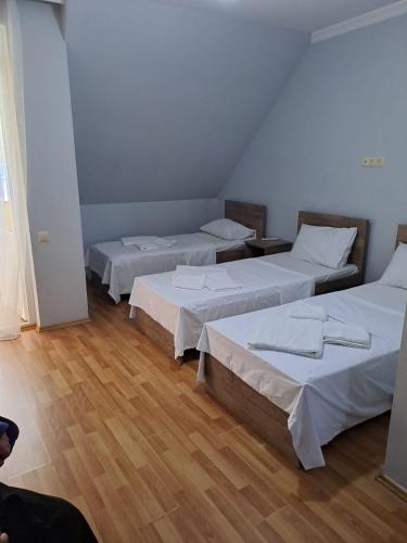 a group of three beds in a room with wood floors at Hotel Zundaga 1 in Batumi