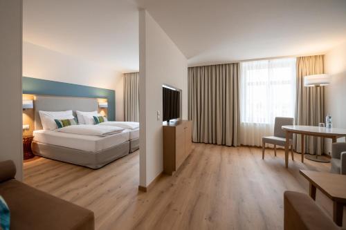 ロッハウにあるSeehotel am Kaiserstrandのベッドとテーブルが備わる広いホテルルームです。