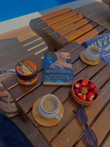 a table with a cup of coffee and a bowl of strawberries at Burzan Bungalovi in Podgorica