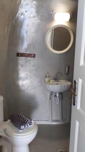 a bathroom with a sink and a toilet and a mirror at Olympic Villas in Oia