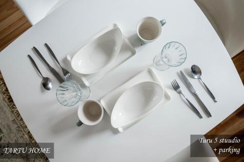 a white table with plates and cups and utensils at City Center Turu str apartments, parking, Tartu Home in Tartu