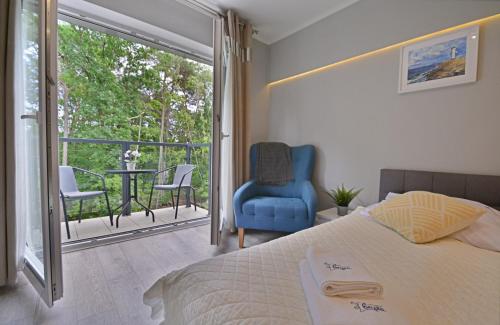 a bedroom with a bed and a balcony with a table and chairs at Apartamenty Cesarskie - Apartamenty Bryza - Parking in Świnoujście