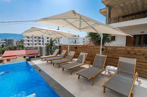 een rij stoelen en een parasol naast een zwembad bij The Lord Hotel in Ksamil