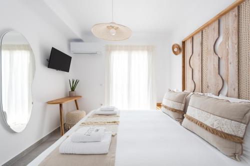 a white bedroom with a large bed and a mirror at Sersi Paros Villas & Suites in Kampos Paros