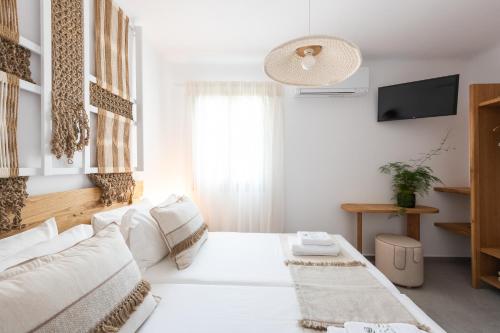a white living room with a white couch and a television at Sersi Paros Villas & Suites in Kampos Paros