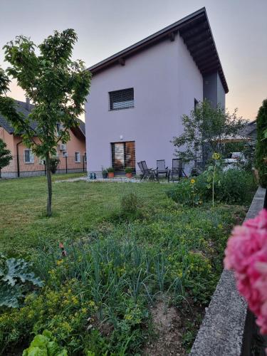 une grande maison blanche avec une cour fleurie dans l'établissement ADRIANs HOUSE, à Domžale