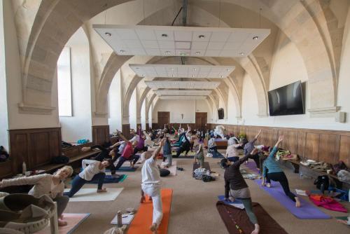 eine Gruppe von Leuten, die in einem großen Raum Yoga machen in der Unterkunft HOSTELLERIE CHARLES de FOUCAULD in Viviers