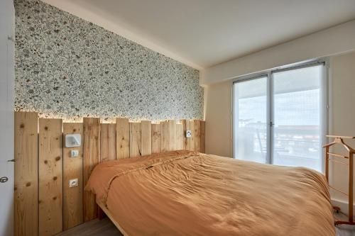 een slaapkamer met een bed met een houten muur bij Le Tikahupo - Charmant appt vue sur le port in Courseulles-sur-Mer