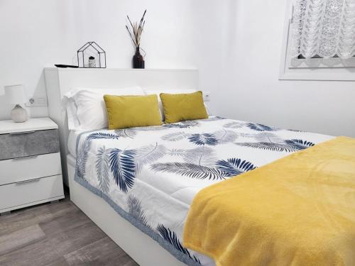 ein weißes Schlafzimmer mit einem Bett mit einer gelben Decke in der Unterkunft Apartamento del Puente in Autol