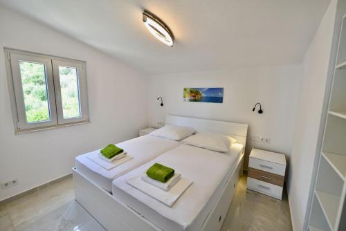 Un dormitorio blanco con una cama blanca y una ventana. en Apartments Petrovac, en Zavala
