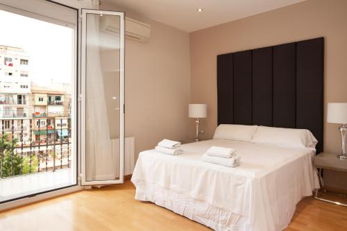 1 dormitorio con cama blanca y ventana grande en Stay U-nique Apartments Sepulveda, en Barcelona