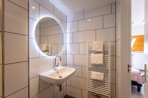 een badkamer met een wastafel en een spiegel bij Hotel Herberg de Lindehoeve in Grubbenvorst