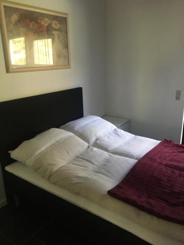 1 cama con sábanas blancas y manta roja en Lerbæk Fiskepark en Frederikshavn