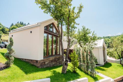 a home with a green yard with trees at Toplik Village Resort in Lukavica