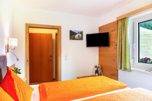 a bedroom with a bed and a window and a television at Haus Alpenheim Apartment 3 in Tux