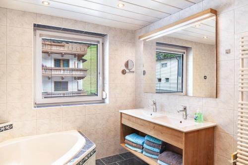 a bathroom with a tub and a sink and a mirror at Haus Alpenheim Apartment 3 in Tux