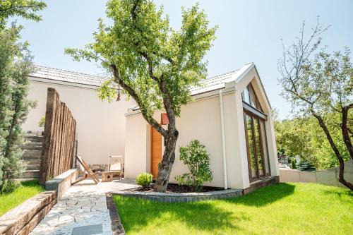 a small white house with a tree in the yard at Toplik Village Resort in Lukavica
