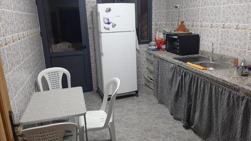een keuken met een witte koelkast en een tafel en stoelen bij Maison N 221 Hay Mohammadi Agadir Maroc in Agadir