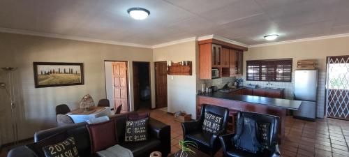 a kitchen and a living room with chairs and a counter at DullVino Apartment @ Millers Cove in Dullstroom