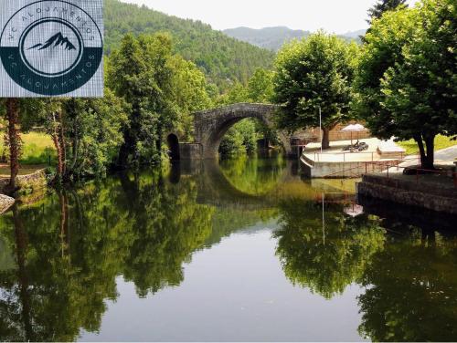 a bridge over a river with a reflection in the water at VC Alojamentos T2 in Seia