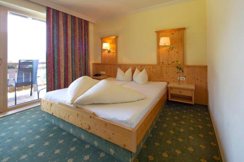 um quarto de hotel com uma cama e uma varanda em Landhaus Obertuschenhof em Pertisau
