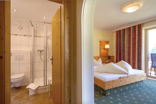 a bedroom with a bed and a bathroom with a shower at Landhaus Obertuschenhof in Pertisau