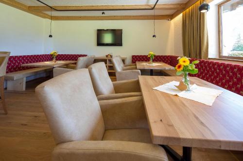 a dining room with tables and chairs and a tv at Landhaus Obertuschenhof in Pertisau