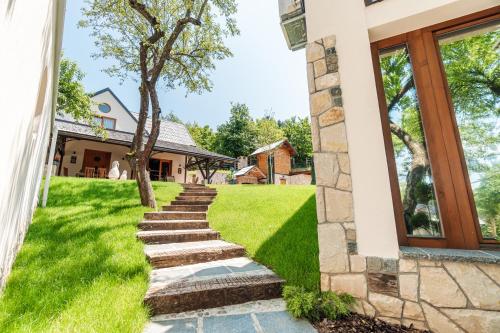 a stone path leading to a house with a tree at Toplik Village Resort in Lukavica
