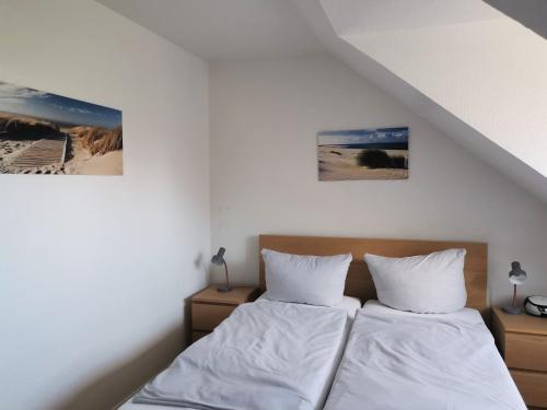 a bedroom with two beds and two pictures on the wall at Ferienhaus Rosenboom Rosenboom 02 in Norderney