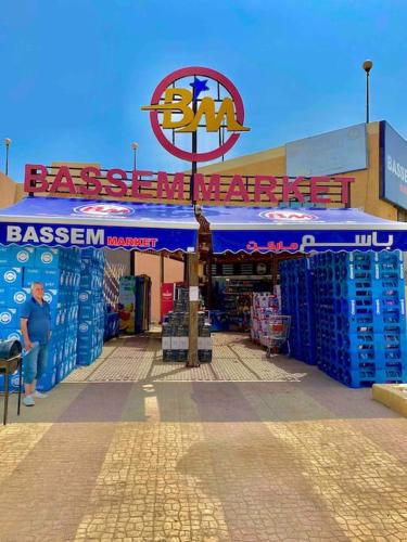 a man standing in front of a store with a sign at 50% Off. 2BR , 2BR Ground floor with pool view, private beach access, security 24/7 شاليه ٢ غرفه ، ٢ حمام ف الدور الارضي قدام جنينه و حمام السباحه مباشره ، شاطيء خاص بالقرية و أمن ٢٤ ساعه و مسجد خاص in Dawwār Muḩammad Abū Shanab