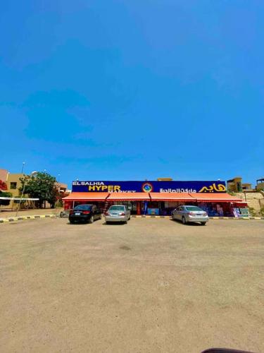 a fast food restaurant with cars parked in a parking lot at 50% Off. 2BR , 2BR Ground floor with pool view, private beach access, security 24/7 شاليه ٢ غرفه ، ٢ حمام ف الدور الارضي قدام جنينه و حمام السباحه مباشره ، شاطيء خاص بالقرية و أمن ٢٤ ساعه و مسجد خاص in Dawwār Muḩammad Abū Shanab