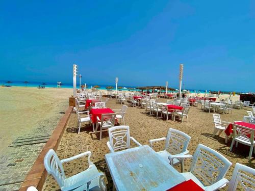 a group of tables and chairs on the beach at 50% Off. 2BR , 2BR Ground floor with pool view, private beach access, security 24/7 شاليه ٢ غرفه ، ٢ حمام ف الدور الارضي قدام جنينه و حمام السباحه مباشره ، شاطيء خاص بالقرية و أمن ٢٤ ساعه و مسجد خاص in Dawwār Muḩammad Abū Shanab