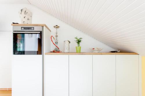 a white kitchen with a shelf on top of cabinets at Green Point in Preserje