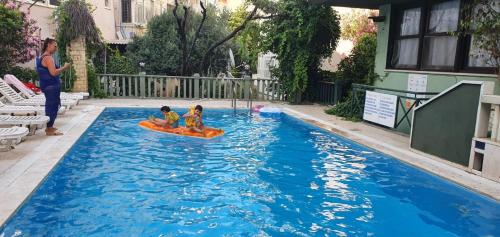 two children riding on a raft in a swimming pool at Antik Apartments Marmaris in Marmaris
