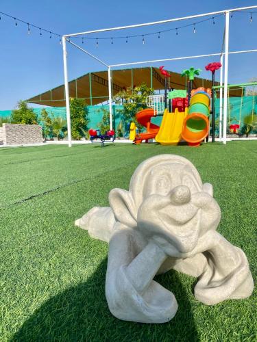 a statue of a child laying on the grass in a playground at Luxury Farm with Swimming Pool and BBQ in Al Rahba
