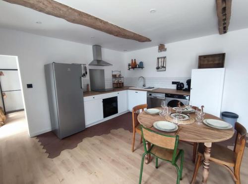 une cuisine avec une table avec des chaises et un réfrigérateur dans l'établissement charme de la campagne proche mer, à Auberville-la-Manuel