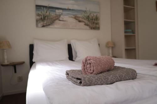 Una cama con una toalla rosa encima. en De Blokhut, en Egmond aan den Hoef
