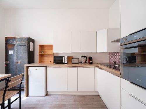 una cocina con armarios blancos y electrodomésticos de acero inoxidable en Montesquieu * Place Stanislas * Idéal Pros, en Nancy