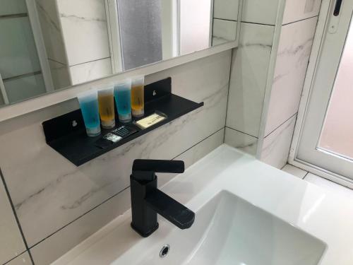 a bathroom sink with a black faucet and glasses on a shelf at Avda Plaza de Toros, apartamento dos dormitorios junto a metro Vistalegre in Madrid