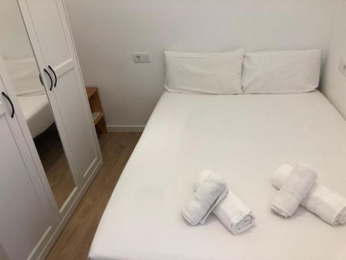 Una cama blanca con dos toallas enrolladas. en Avda Plaza de Toros, apartamento dos dormitorios junto a metro Vistalegre, en Madrid