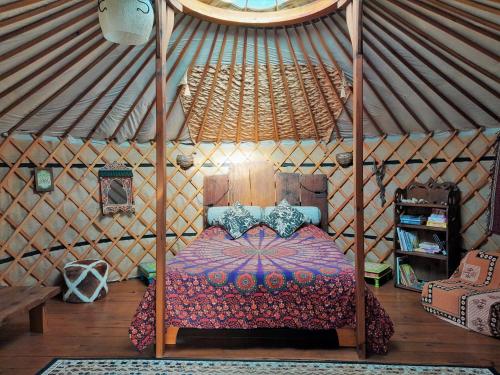 - une chambre avec un lit à baldaquin dans une yourte dans l'établissement Green Man yurt, à Penela