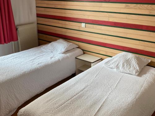 2 camas en un dormitorio con una pared a rayas en Hôtel Les trois maures, en Verdun-sur-le-Doubs