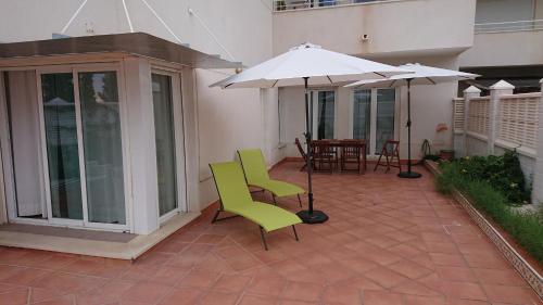 a patio with two green chairs and an umbrella at Cabo de Gata - Playa y Golf - Retamar El Toyo in El Toyo