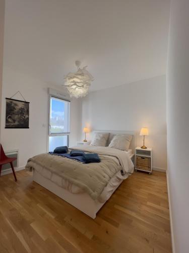 une chambre blanche avec un grand lit et une fenêtre dans l'établissement Appartement vue mer, à Carantec