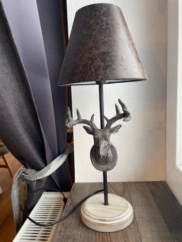 a lamp with a fake deer head on a table at Harzstübl25 in Sankt Andreasberg