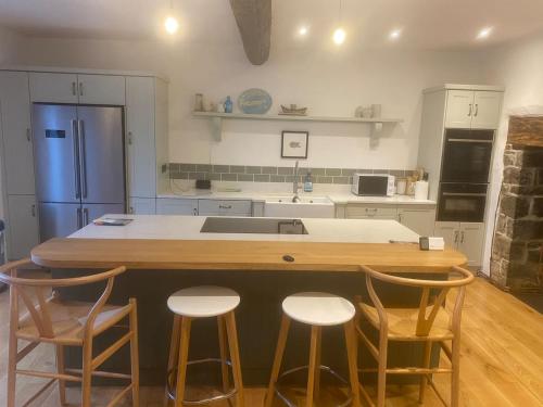 a kitchen with a kitchen island with four stools at Upcott Farm in Lapford