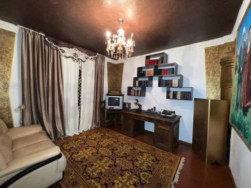 sala de estar con sofá, escritorio y lámpara de araña en Naryn Cozy House en Naryn